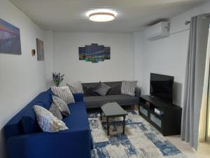 a living room with a blue couch and a television at Achilles Heel in Kornos