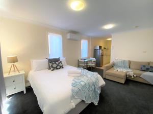 a bedroom with a large bed and a couch at Poley Cow Studio Lakeviews in Jindabyne