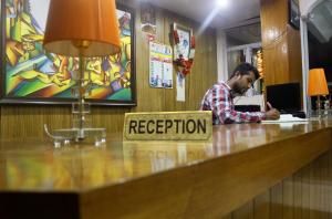 a man sitting at a bar with a registration sign at Hotel Himshikhar in Chaukori