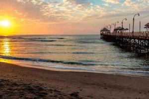 a pier on the beach with the sunset in the background at Exclusivo y acogedor con ascensor Directo en Urbanización la Merced in Trujillo