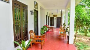 a porch of a house with wooden chairs and tables at Smashing Inn in Dambulla