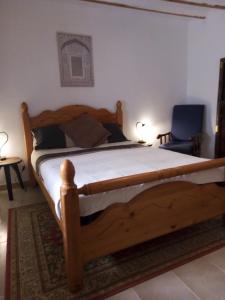 1 dormitorio con cama de madera y silla azul en Casa en la Plaza, Hinojares Vivienda Rural, en Hinojares