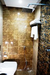 a bathroom with a toilet and a tile wall at HOTEL SHIVOY GRAND in Varanasi
