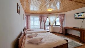 a bedroom with two beds and a wooden ceiling at La Vulturi in Fundata