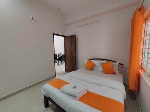 sypialnia z 2 łóżkami z pomarańczowymi i białymi poduszkami w obiekcie Meer Stay - Premium Service Apartments w mieście Vānivilāsa Puram