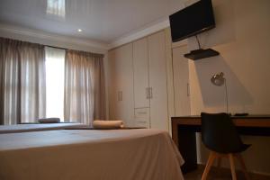 a bedroom with a bed and a desk and a television at Hush Guest House in Northam