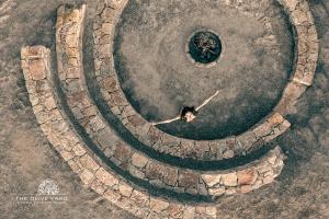 a man is standing in a stone circle at The Olive Yard in Gythio