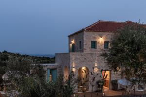 an old stone house with lights on it at night at The Olive Yard in Gythio