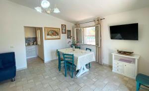 a dining room with a table and a television at Santu Juanne -Ammentos Posada- a due passi dalla spiaggia in San Giovanni