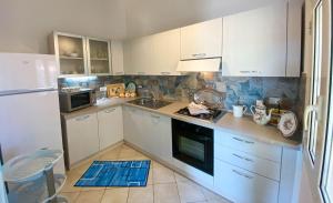 a kitchen with white cabinets and a white refrigerator at Santu Juanne -Ammentos Posada- a due passi dalla spiaggia in San Giovanni +27 photos