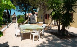 a table and chairs in a yard with a palm tree at Santu Juanne -Ammentos Posada- a due passi dalla spiaggia in San Giovanni