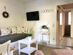 Una sala de estar con un sofá y un televisor en la pared. en Bungalow 68 am Waldrand, en Glowe