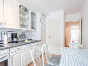 a kitchen with white cabinets and a table with chairs at Ferienwohnung Naurulokki in Baabe