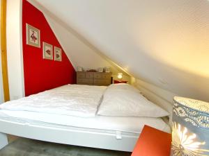 uma cama branca num quarto com uma parede vermelha em Ferienhaus Sabrina em Sassnitz
