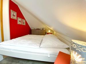 a white bed in a room with a red wall at Ferienhaus Sabrina in Sassnitz