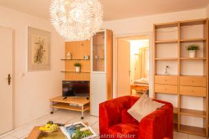a living room with a red chair and a table at Ferienhaus am Ufer - Ferienwohnung Strandsand in Sassnitz