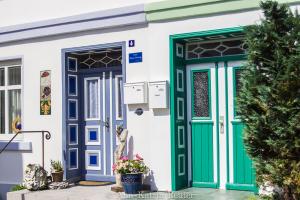 a house with blue and green doors and flowers at Ferienhaus am Ufer - Ferienwohnung Strandsand in Sassnitz