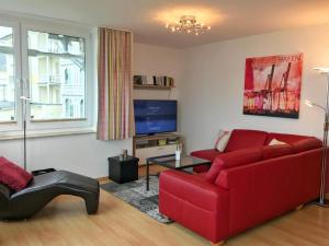 ein Wohnzimmer mit einem roten Sofa und einem TV in der Unterkunft Villa Seeblick - Ferienwohnung 407 in Sassnitz