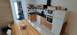 a small kitchen with a table and a white refrigerator at Chaleureuse petite maison de bourg in Beaumont-sur-Sarthe