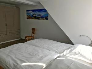 ブレーゲにあるFerienwohnung am Hochzeitsbergのベッドルーム(白いベッド1台、椅子付)