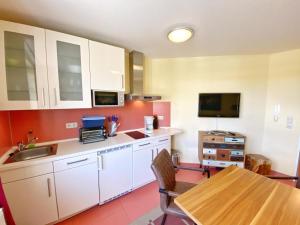 a kitchen with white cabinets and a wooden table at Appartements am Rondell Neddesitz, Appartement 305 in Neddesitz