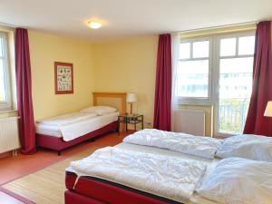 Duas camas num quarto com cortinas vermelhas em Appartements am Rondell Neddesitz, Appartement 305 em Neddesitz