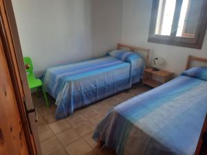 1 dormitorio con 2 camas y silla verde en Casa di Max, en Torre dell'Orso