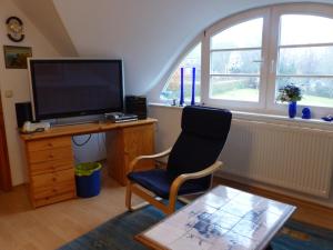 a living room with a chair and a flat screen tv at Ferienwohungen im Feriengarten DG in Nardevitz