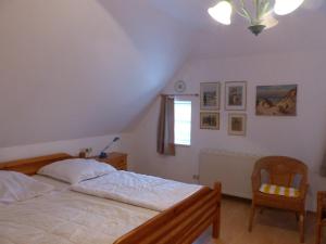 a bedroom with a bed and a chair and a window at Ferienwohungen im Feriengarten DG in Nardevitz