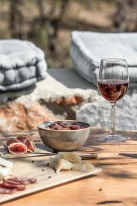 a glass of wine sitting next to a bowl of fruit and a bowl of food at The Olive Yard in Gythio