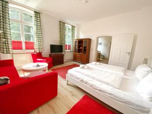 ein Schlafzimmer mit einem weißen Bett und einem roten Sofa in der Unterkunft Gutshof Dubnitz - Ferienwohnung 1 "Carlo" in Sassnitz