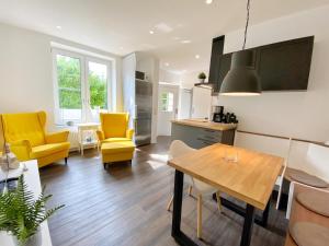 a kitchen and living room with yellow chairs and a table at Gross Stresow Ferienwohnung Vilm E in Groß Stresow