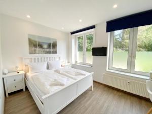 a white bedroom with a white bed and two windows at Gross Stresow Ferienwohnung Vilm E in Groß Stresow