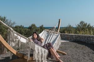 a woman is sitting in a hammock at The Olive Yard in Gythio