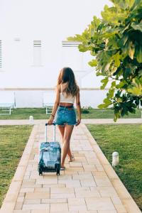 a woman walking with a suitcase on a sidewalk at B&B Domus Terra Mare in Torre San Giovanni Ugento