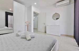 a white bedroom with a large bed and a mirror at Sea view apartment in Birżebbuġa