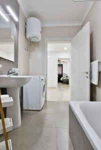 a white bathroom with a sink and a tub at Sea view apartment in Birżebbuġa