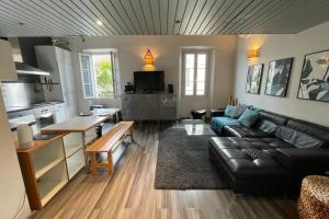 a living room with a black leather couch and a kitchen at 2 bedroom duplex apartment in the center of Cannes in Cannes