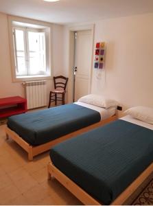 Un dormitorio con dos camas y una silla y una ventana. en casa vacanze L'Altra Diaz, en Siracusa