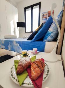 uma mesa com um prato de croissants e uma cama em Bilocale Clotilde seconda fila mare em San Benedetto del Tronto