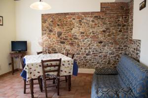 een eetkamer met een tafel en stoelen en een bakstenen muur bij Room in Farmhouse - Hortensia apartment in Chiesina Uzzanese