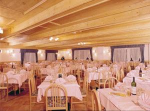 una sala da pranzo con tavoli e sedie bianchi di Hotel Cielo Blu a Passo del Tonale