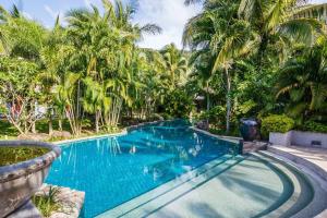 a swimming pool in a resort with palm trees at Villa in the Park, Whole house's suitable for family's vacation in Phuket Town