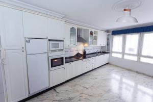 duża biała kuchnia z białymi urządzeniami i oknami w obiekcie Casa Clara, acogedora en el centro del pueblo w mieście Corcubión