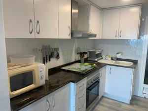 a kitchen with white cabinets and a microwave at Primera línea en Cullera con piscina. Inmejorables vistas in Cullera
