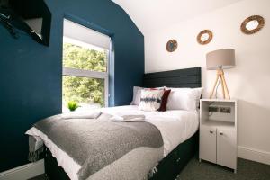a bedroom with blue walls and a bed with a window at Contractor & Leisure & En-Suite Bathrooms & Free Parking in Derby