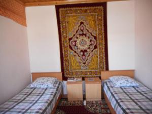 Habitación con 2 camas y alfombra en la pared en OPTIMIST en Samarcanda