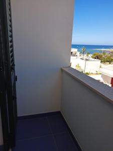 a room with a balcony with a view of the ocean at Casa Vacanza in Torre San Giovanni Ugento
