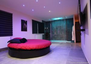 a bedroom with a red bed and a shower at Ds Plaisir Love Room avec sauna, jacuzzi à Nancy in Nancy