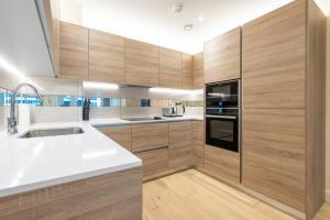 uma cozinha com armários de madeira e um balcão branco em Lovely 2 bed Condo London em Woolwich